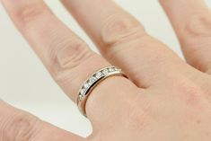 a woman's hand with a wedding ring on top of her finger, against a white background