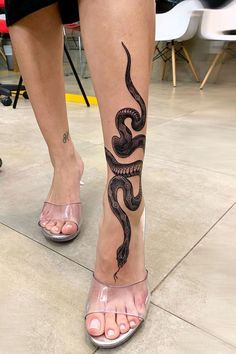 a woman's legs with a snake tattoo on them