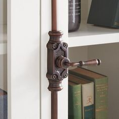 an old door handle is on the side of a book shelf next to some books