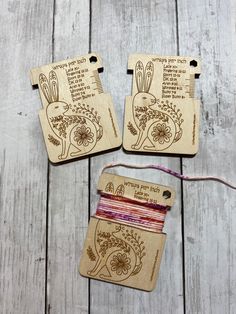 three wooden tags with designs on them sitting on top of a white wood table next to a string