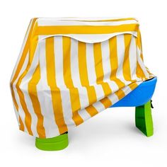 a yellow and white striped cover sitting on top of a green plastic table with blue legs