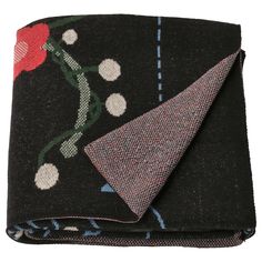 a black blanket with a red flower and polka dot design on the bottom, next to a folded piece of fabric