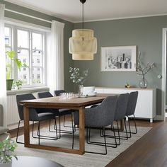 a dining room table with grey chairs in front of a window