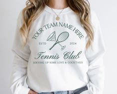 Introducing our Custom Tennis Team Sweatshirt, the perfect blend of style, comfort, and personalization for your team! This high-quality sweatshirt allows you to showcase your team spirit with a unique design that can be fully customized. At the top, proudly display your team name, making it clear who you represent. In the center, mark the year to commemorate your season or special event. At the bottom, add your custom phrase to inspire, motivate, or simply bring a smile to your teammates' faces Collegiate Sports Top With Custom Logo, Athleisure Long Sleeve Team Name Sweatshirt, Long Sleeve Athleisure Sweatshirt With Team Name, Athleisure Long Sleeve Sweatshirt With Team Name, Sporty Tops With Custom Logo For Sports, Sporty Crew Neck Hoodie For Team Events, Team-colored Tops With Custom Logo For Team Events, Team Spirit T-shirt For Sports Season, Team Spirit T-shirt With Branding For Sports Season