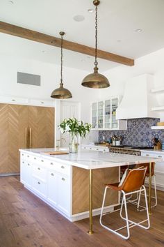 a kitchen with two pendant lights hanging from the ceiling and an island in the middle