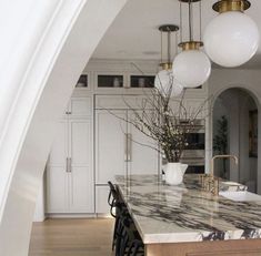 a large kitchen with marble counter tops and gold accents on the ceiling, along with white cabinets