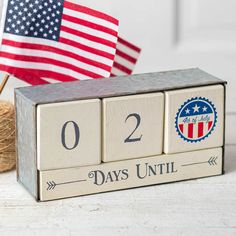 a wooden block calendar with an american flag in the background