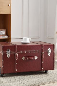 a red suitcase sitting on top of a rug next to a coffee table and bookcase