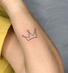 a woman's arm with a tattoo on it that has a crown in the middle