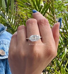 a woman's hand with a ring on it and palm trees in the background