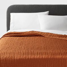 an orange bedspread with two white pillows