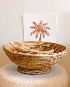 two baskets sitting on top of a stool with a palm tree in the middle of it