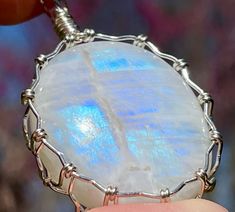 Welcome to the Realm of the Fae and crystal jewelry fit for a Faerie Queen!  It's a magical, faerie tale realm of all things beautiful, sweet, and sparkly!   This is a gorgeous Rainbow Moonstone pendant! Flashes of brilliant blue light can be seen as the sun is reflected off of this precious gemstone. It has been Lovingly wrapped in sterling silver wire and will come, ready to wear, on a 1mm adjustable length, black cotton cord. This pendant is 1.8" long, 1.25" wide, .06" depth. "Rainbow Moonstones celebrate and honors the Divine Feminine Energy. It shines the light within to explore one's inner mysteries, depths, and the unknown. Moonstones increase inner knowing, higher wisdom, intuition, and all forms of psychic abilities. It promotes harmony, assists in finding balance and peace amidst Berkeley Springs Wv, Faery Queen, Inner Knowing, Divine Feminine Energy, The Fae, Magic Stones, Shine The Light, Protection Crystals, Rainbow Moonstone Pendant