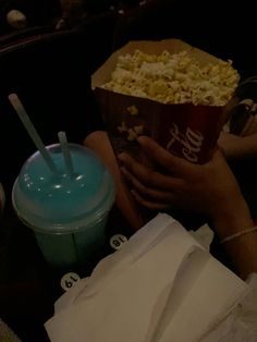 a person is holding a cup and eating popcorn