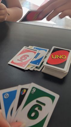 several playing cards on a table with someone's hand reaching for the one card