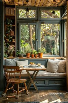 a table and chairs in front of a window with potted plants