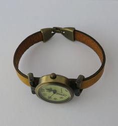 This is a aged bronze finish metal alloy round watch, 1 inch diameter. Quartz, analog, battery operated (battery included). The metal is free of nickel and lead. The band is made in leather and the closure is folding over type also made in aged bronze finish alloy metal. Will be made to fit your wrist. Please select the measurement of your wrist in inches at the checkout. You can measure your wrist putting a piece of paper or a cord around your wrist (not too tight not too loose) and the measure Vintage Adjustable Metal Watch Accessories, Brown Adjustable Watch Accessories With Metal Dial, Brown Watch Accessories With Metal Dial And Adjustable Fit, Simple Watches, Retro Minimalist, Round Watch, Minimalist Watch, Aged Bronze, Watch For Women