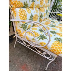 a white iron frame couch with yellow pineapple cushions