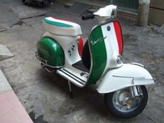 a scooter is parked on the street in front of a building with an italian flag painted on it