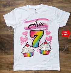 a white shirt with the number seven on it and cupcakes in rainbow colors