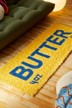 a yellow rug with the word butter on it in front of a couch and chair