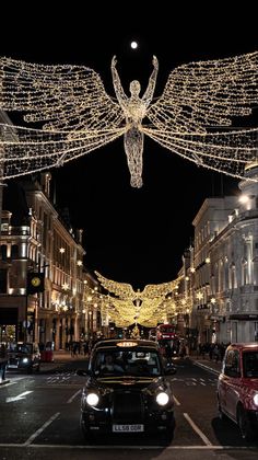 a car driving down a street with christmas lights strung across the road and angel decorations above it