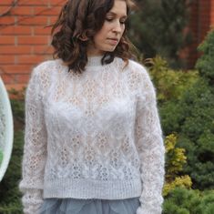 a woman wearing a white sweater and blue tulle skirt standing in front of a brick wall