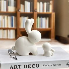 an elephant figurine sitting on top of a book in front of a bookshelf