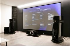 a flat screen tv sitting on top of a wooden table next to speakers and an entertainment system