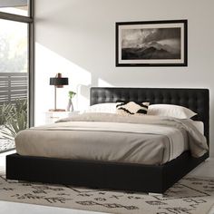 a bedroom with a bed, rugs and pictures on the wall above it in front of a window