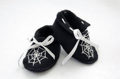 a pair of black baby shoes with spider webs on them