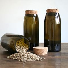 three bottles with different types of food in them on a wooden table next to a corked jar