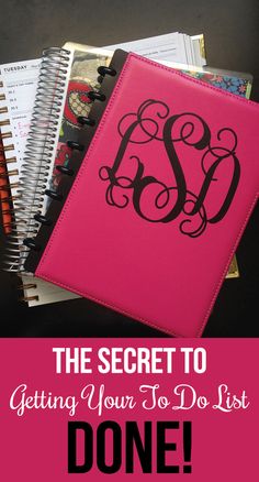 a pink notebook with black monogrammed initials on the front and bottom, sitting next to an open spiral bound book