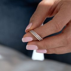 a woman's hand holding a ring with three rows of diamonds on top of it