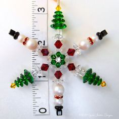 a snowflake made out of glass beads and other christmas decorations on a ruler