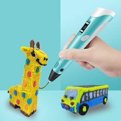 a hand holding a pen next to a giraffe and a toy bus on a blue background