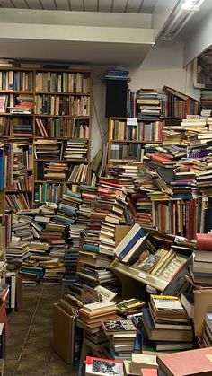 a room filled with lots of books on top of floor next to a wall full of books