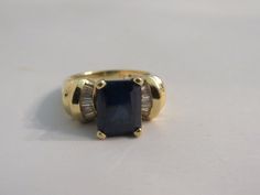 1.     Sapphire, Diamond, 14K Yellow Gold Ring – Size 7 ¼ Striking ring with a rectangular cut dark sapphire in the center and fanned diamonds on either side.  There is a lot of height to this yellow gold setting.  Stamped: 14K.  Dimensions: ¾” across the top and 1 1/8” overall (on the side top to bottom).  Size: 7 ¼.  6 grams/0.2 ounces. Dark Sapphire, Yellow Gold Setting, Yellow Gold Ring, Sapphire Diamond, Yellow Gold Rings, Gold Ring, Gold Rings, Jewelry Watches, Jewelry Rings