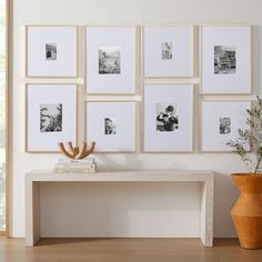 a white table sitting in front of a wall filled with framed pictures and vases