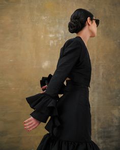 a woman in a black dress is standing with her hands on her hips and looking off to the side