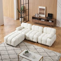 a living room with a white couch and coffee table on top of a rug in front of a wooden wall