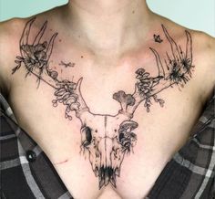 a woman with a tattoo on her chest has flowers and deer's head in the middle