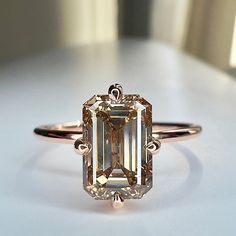 an emerald cut diamond ring on a white surface