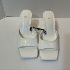 New Zara White Patent Finish Heeled Slides W/Geometric Heel Nwt 6.5/37. There Is A Small Scuff Mark On The Left Front Corner - See Photo. Price Reflects This. Summer Office Mules With 4-inch Heel, White Closed Toe Sandals For Office, White Round Toe Sandals For Office, White Patent Leather Block Heels, Trendy White Mules With Padded Heel, White Mules With Heel Strap For Party, Trendy High Heel Office Sandals, Trendy Open Toe Office Heels, Trendy Open Toe Heels For Office