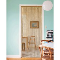 a room with a table and chairs next to a door that has vertical blinds on it