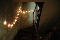 some lights are hanging on the wall next to stairs