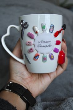 a person holding a coffee mug with different nail polishes on it