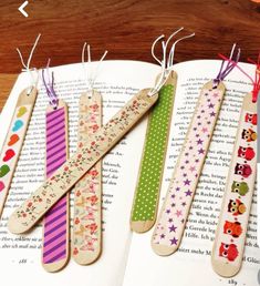 five wooden bookmarks are lined up on top of an open book with colorful designs