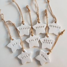 six ceramic star ornaments with words on them hanging from twine strings, tied together