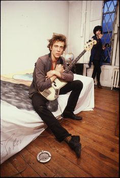 a man sitting on top of a bed holding an electric guitar